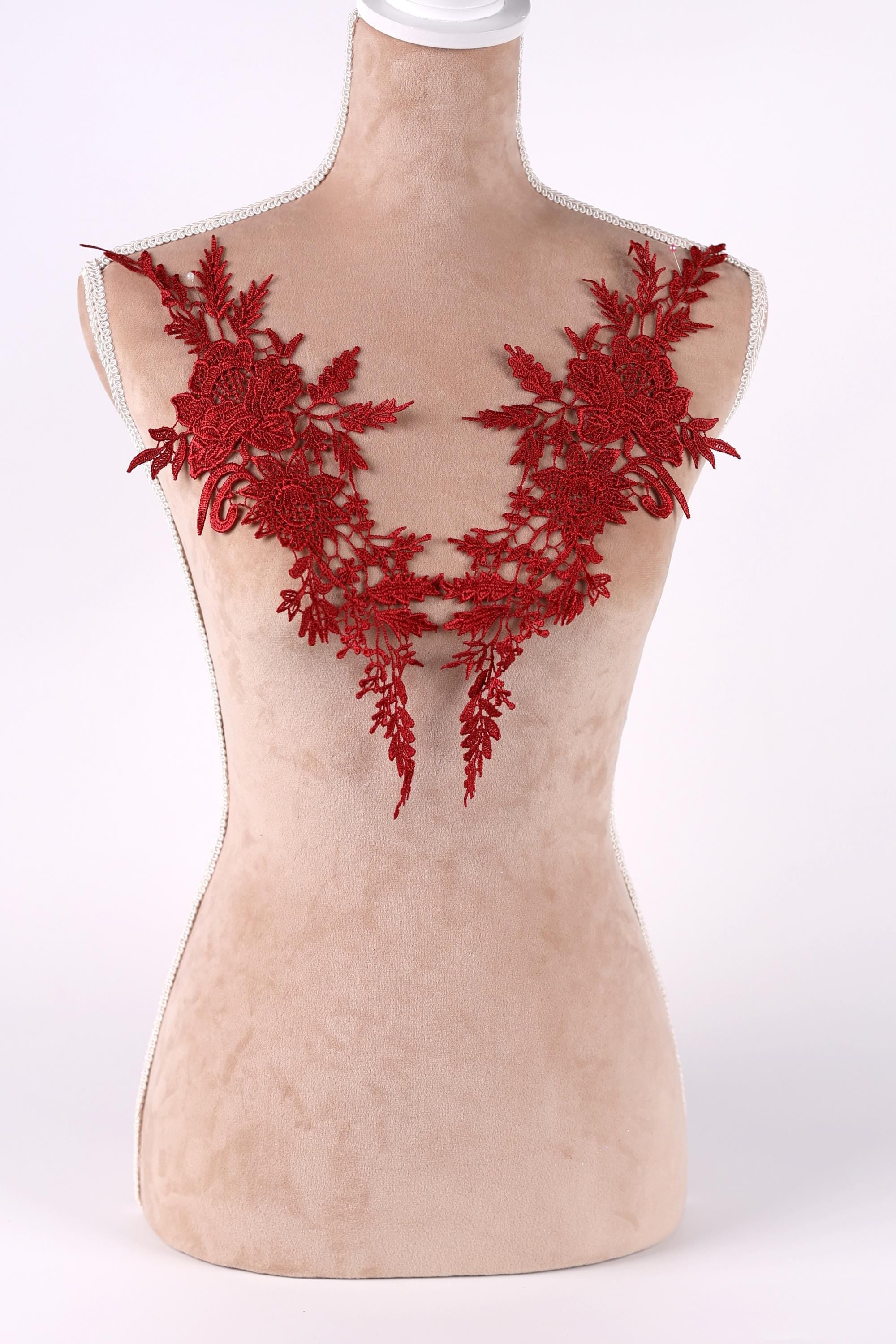 A mannequin wearing a red floral embroidered shoulder piece.
