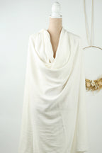A mannequin wearing a white, flowing garment is displayed against a white background.