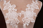 A close-up view of a mannequin torso wearing a white lace dress with intricate floral embroidery.