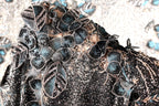 The image is a close-up of a black and blue sequined dress with intricate floral and leaf designs.