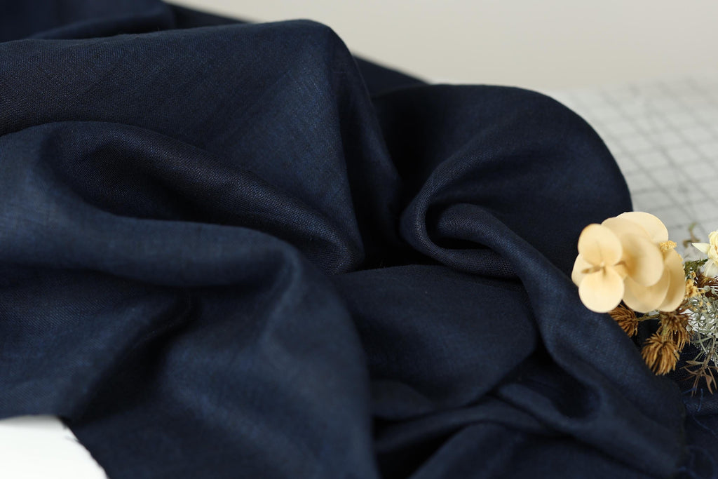 a close-up view of a dark blue fabric, with a small white flower resting on top of it.