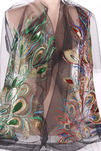 a close-up view of a woman's torso wearing a sheer, black dress with a vibrant, colorful, and intricate embroidered design.