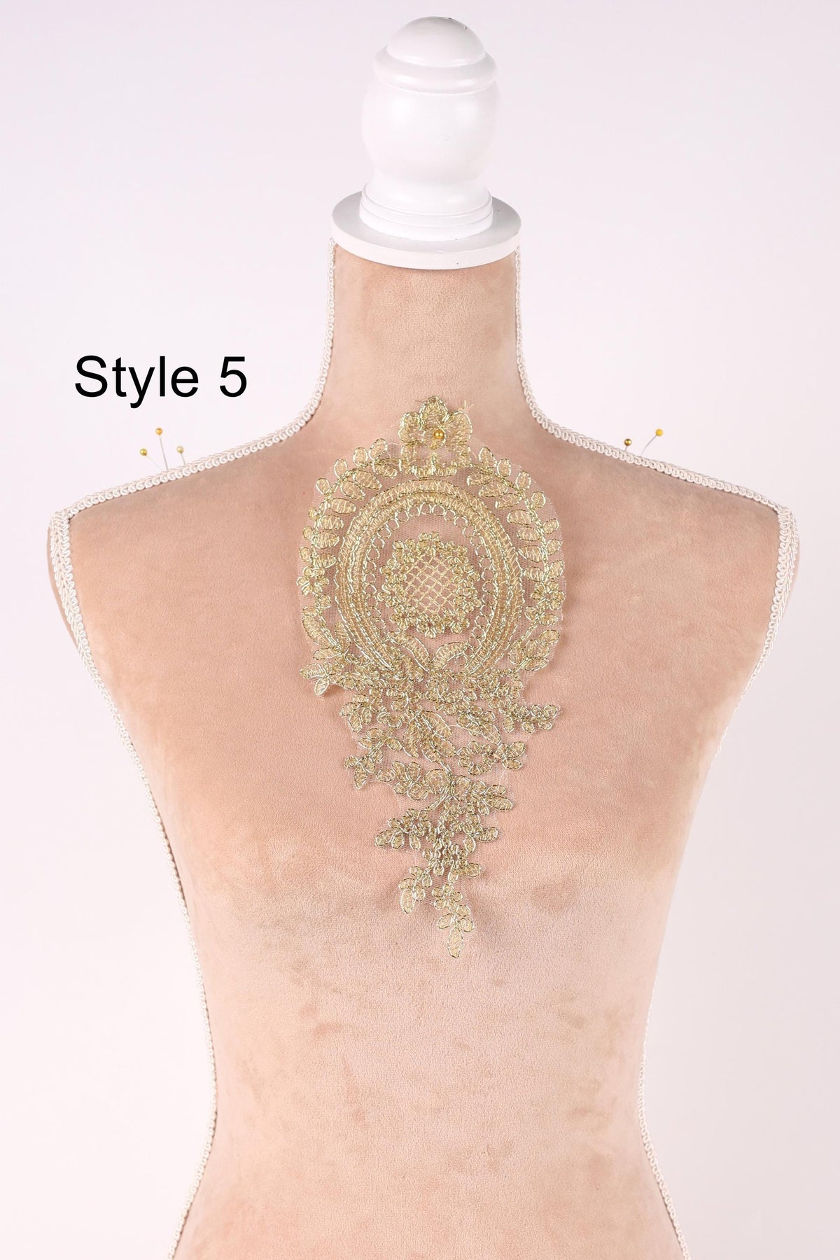 A mannequin with a decorative gold embroidered piece on its back.