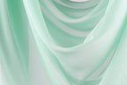 The image is a close-up of a light green fabric, possibly a sheer or sheer-like material, with a soft, flowing texture. The fabric appears to be draped or draped over a surface, creating a sense of movement and softness.