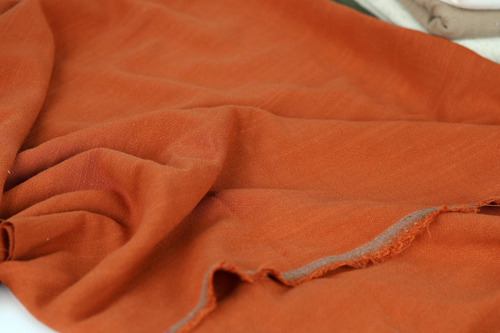a close-up view of a crumpled orange fabric, with visible folds and creases.