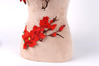a close-up view of a beige fabric with red flower embroidery on it.