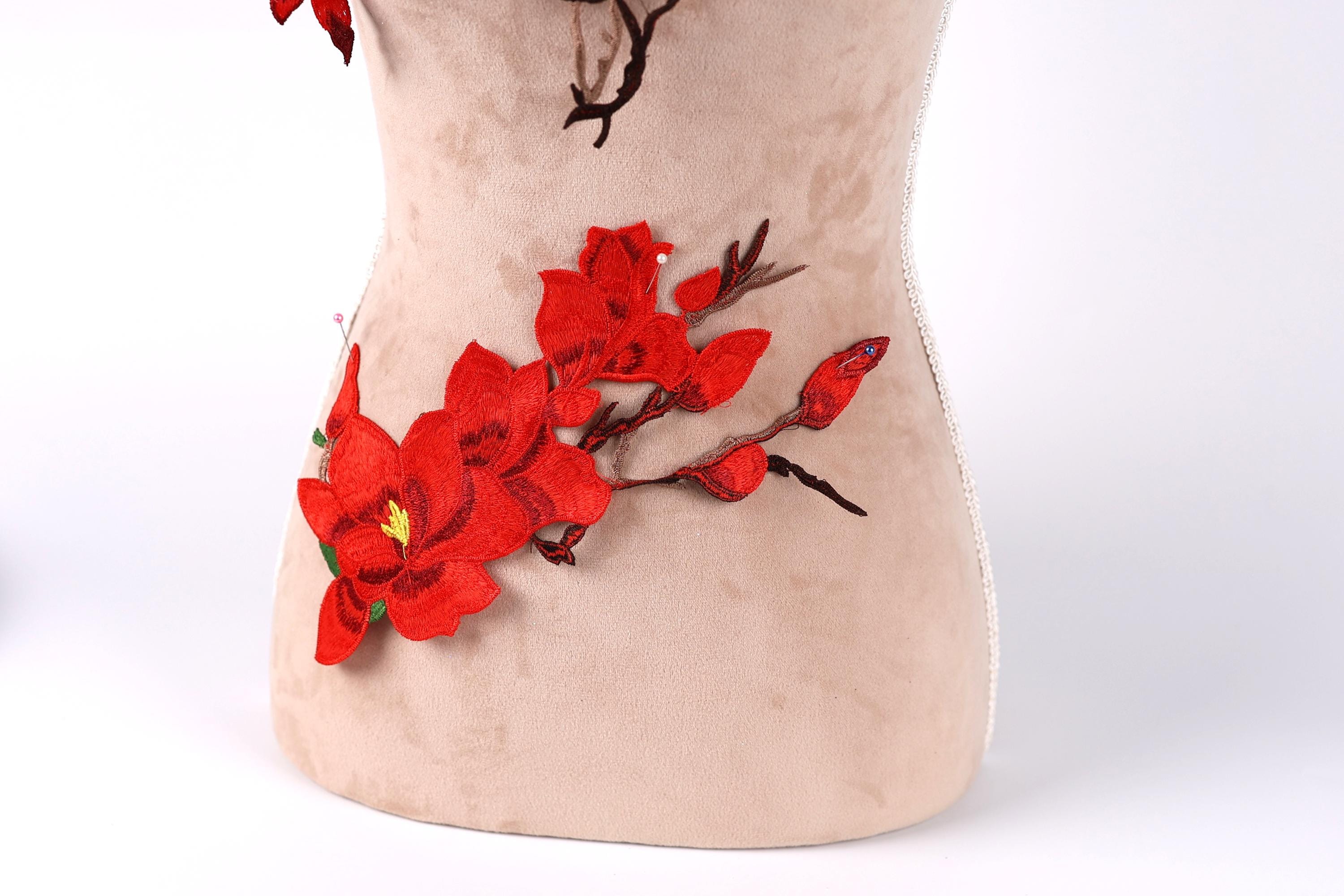 a close-up view of a beige fabric with red flower embroidery on it.
