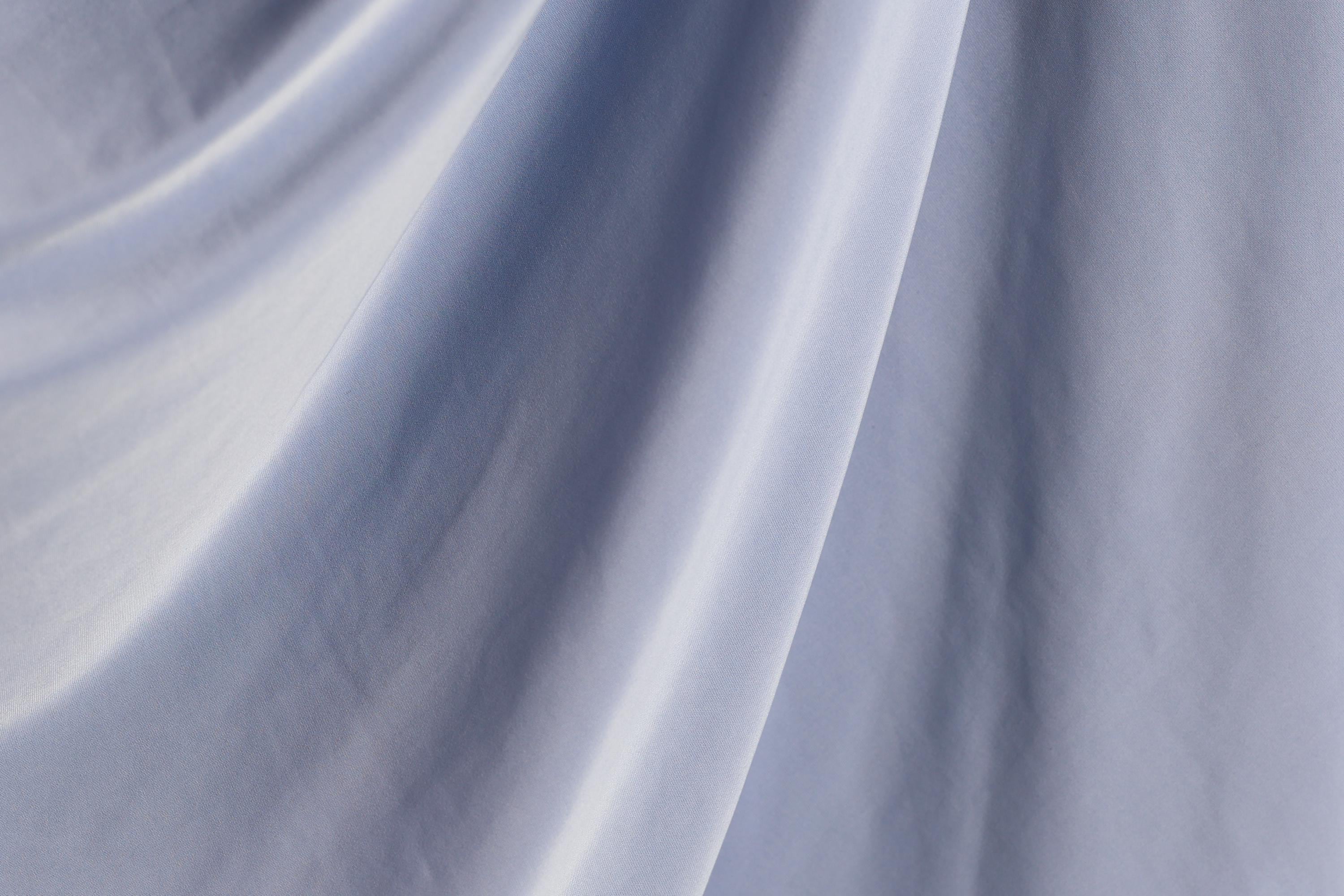 a close-up view of a blue fabric, possibly a piece of clothing or a textile. The fabric appears to be wrinkled and has a smooth texture, suggesting it might be made of a soft, flowing material.