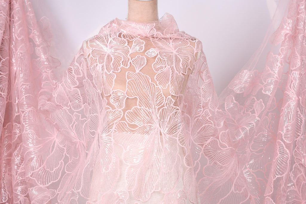 A mannequin wearing a pink lace dress with a floral pattern.