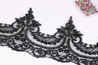 a close-up view of a black lace trim with intricate floral and scroll designs.
