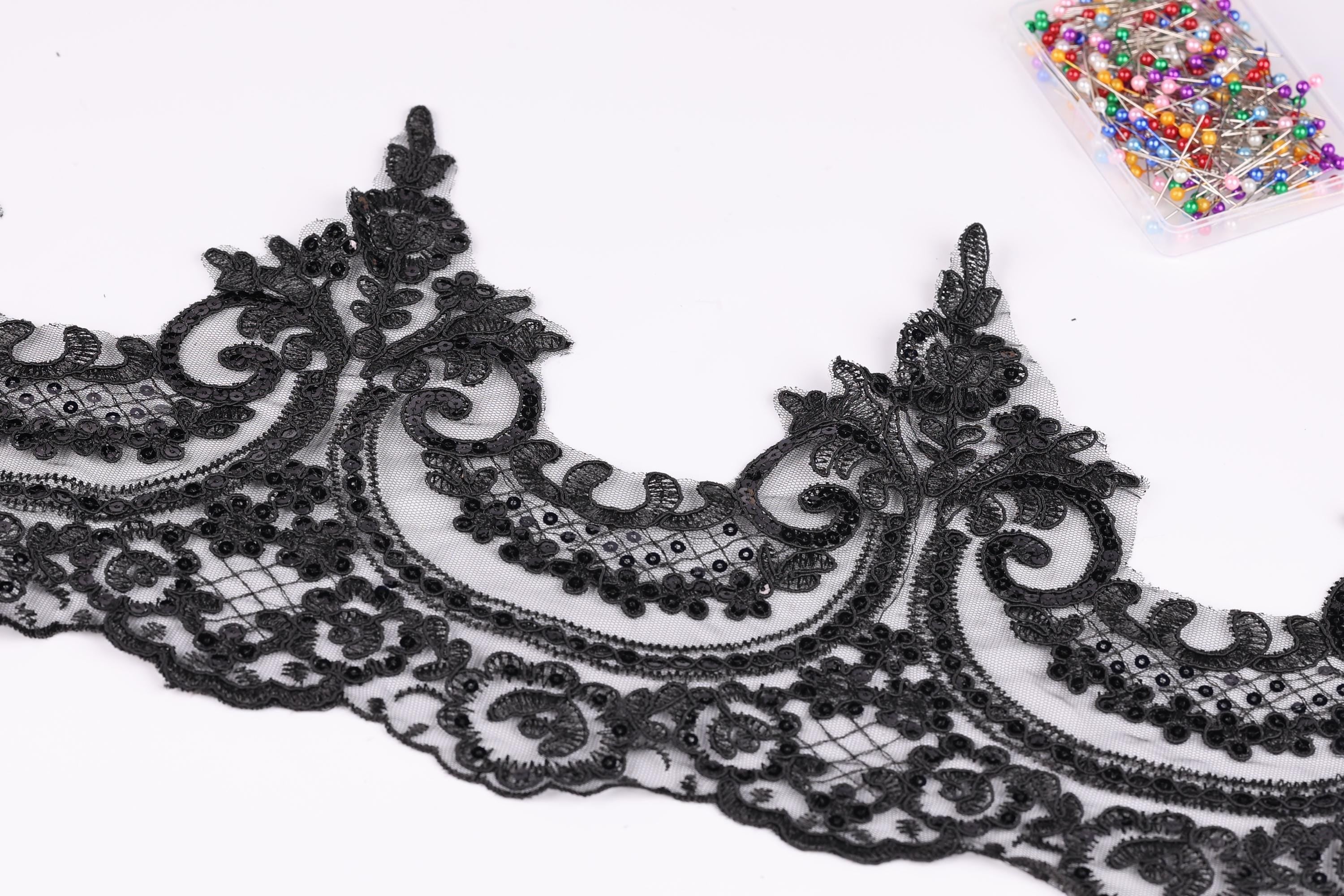 a close-up view of a black lace trim with intricate floral and scroll designs.