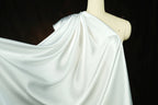 A mannequin wearing a white satin garment with a flowing, draped appearance.