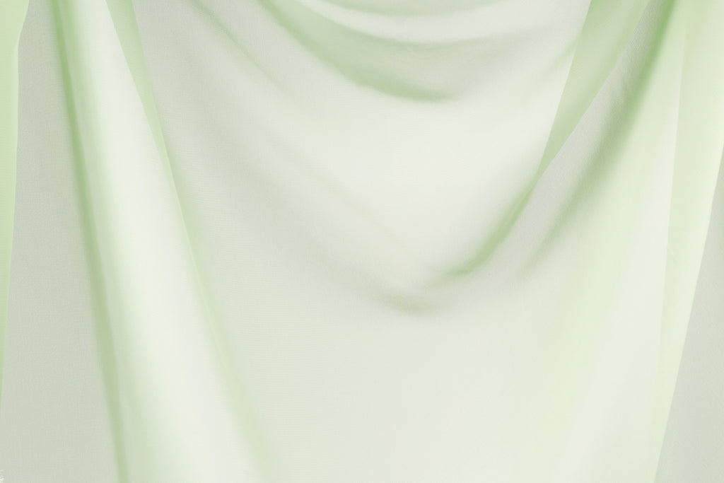 The image is a close-up of a light green fabric, possibly a sheer or sheer curtain, with a soft, flowing texture.
