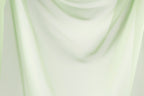 The image is a close-up of a light green fabric, possibly a sheer or sheer curtain, with a soft, flowing texture.