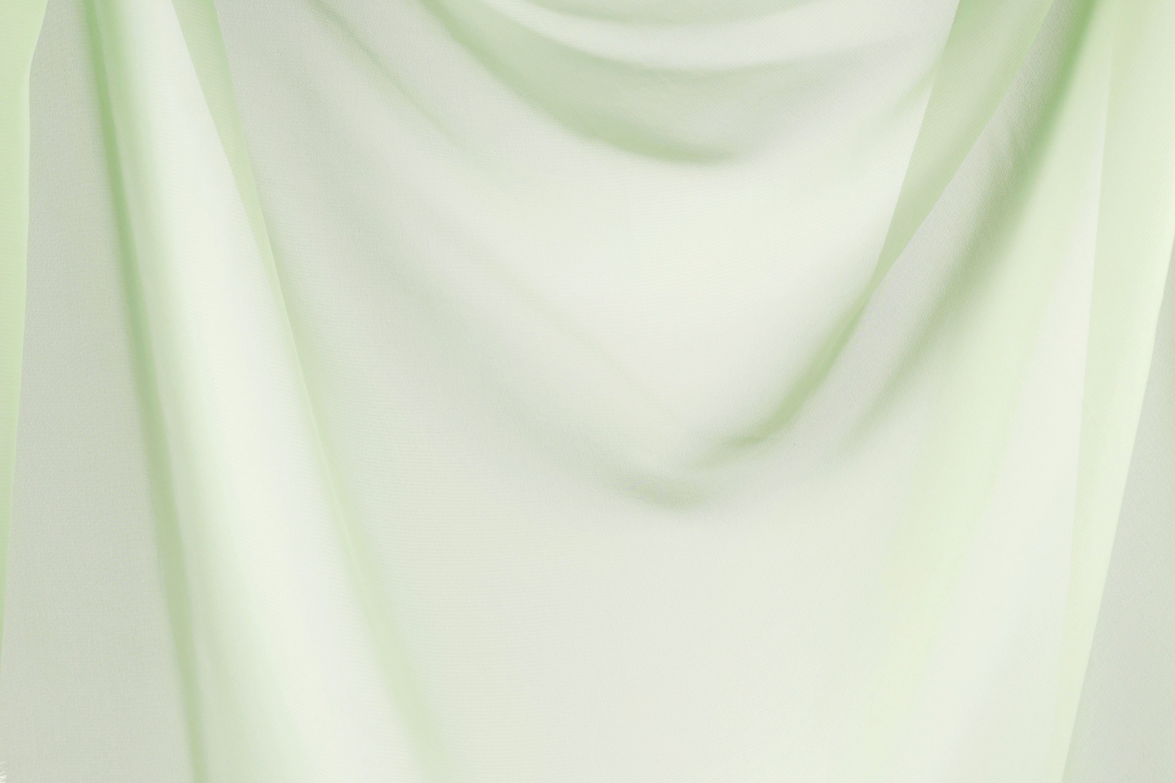 The image is a close-up of a light green fabric, possibly a sheer or sheer curtain, with a soft, flowing texture.