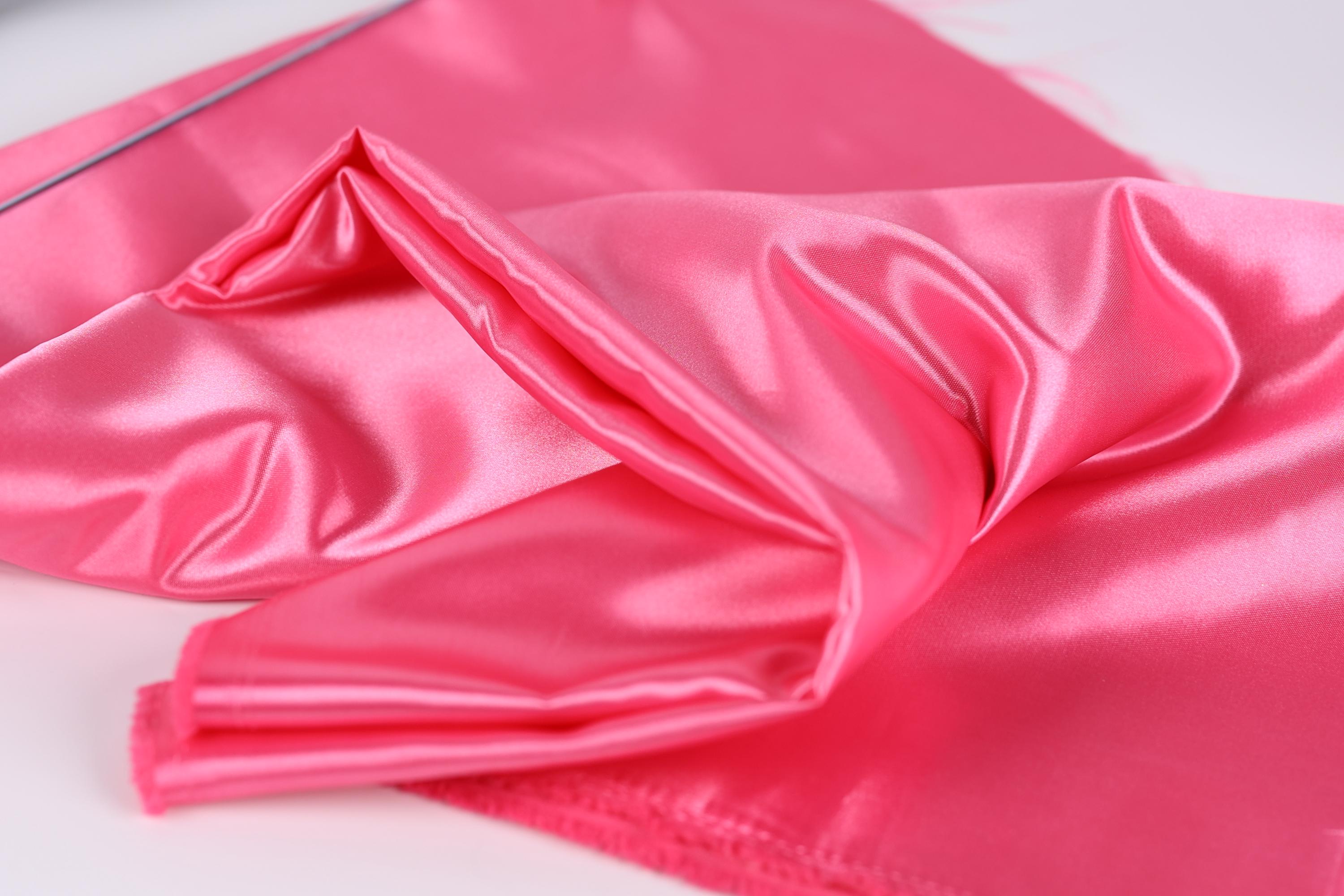 A close-up image of a shiny, pink satin fabric.