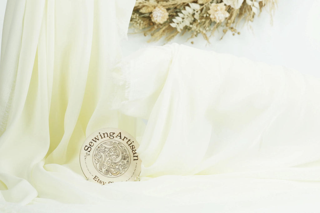 a white fabric with a round wooden plaque in the center, which reads &quot;Sewing Artist&quot;.