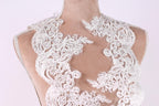 A close-up view of a mannequin wearing a white lace dress with intricate floral patterns.