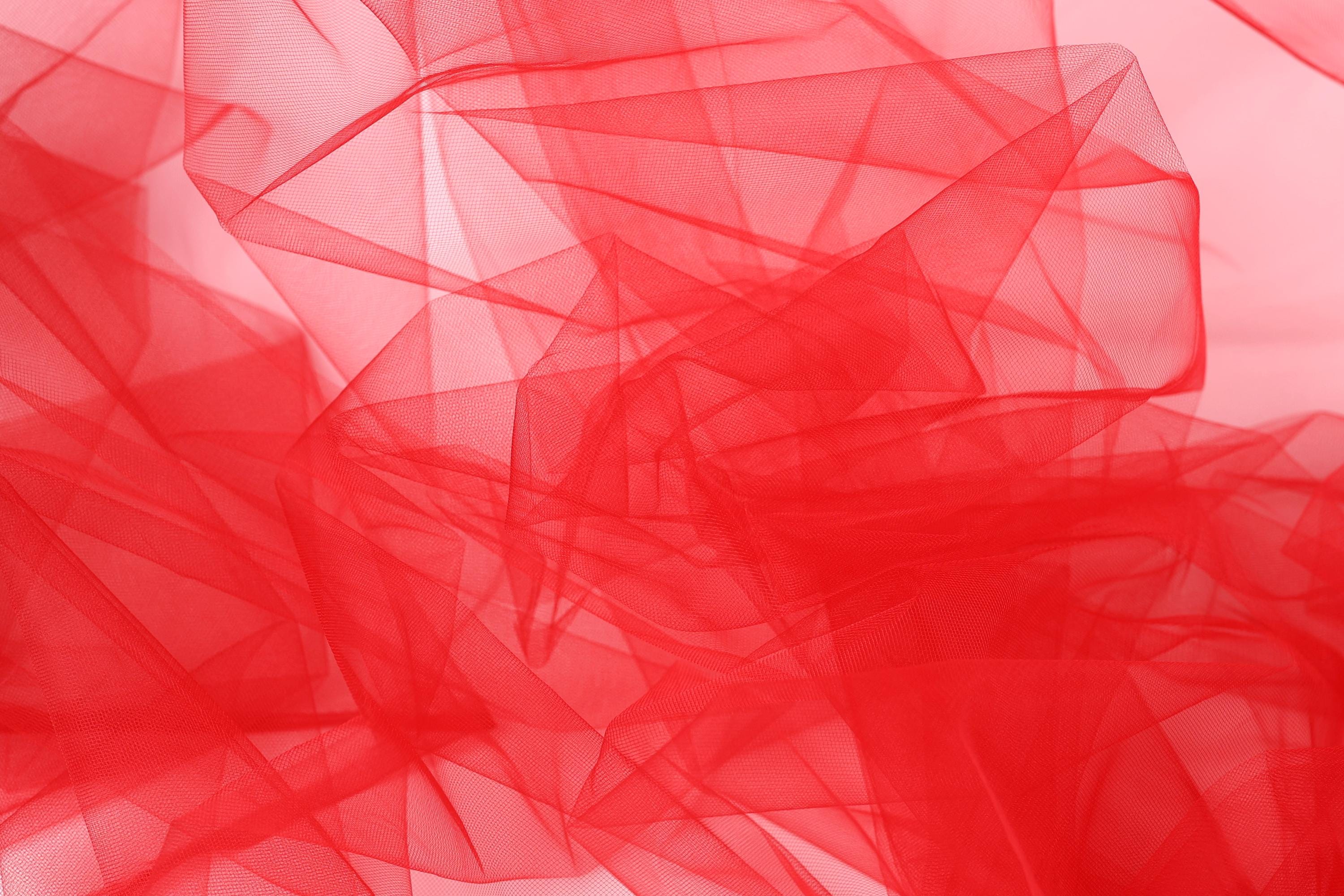 The image is a close-up of a red, translucent fabric with a textured, layered appearance.