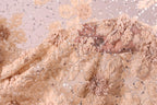 a close-up view of a delicate, intricately embroidered fabric with a floral pattern. The fabric appears to be made of a light-colored material, possibly lace or chiffon, and is adorned with small, sparkling beads or sequins that add a touch of elegance and sparkle to the design. The fabric is folded and draped, showcasing the detailed craftsmanship and artistry involved in its creation.
