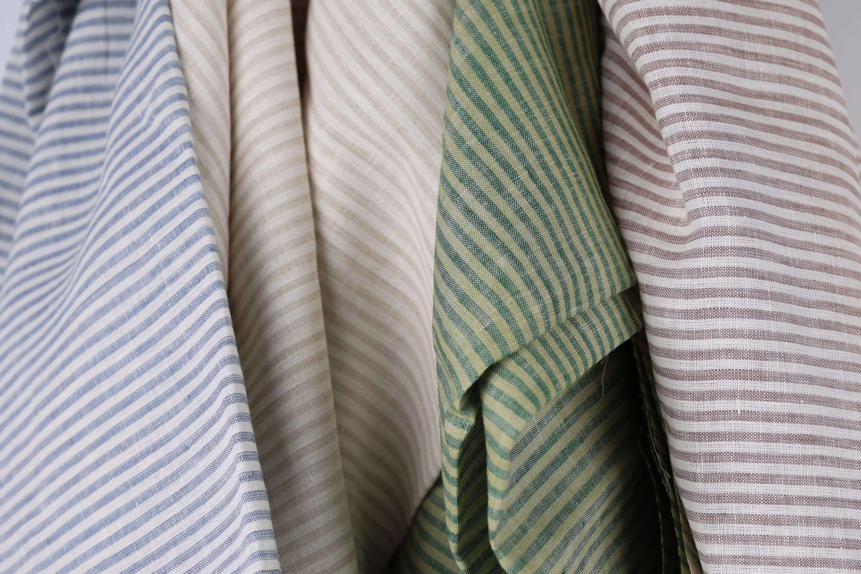 a close-up view of several fabric swatches with different striped patterns, including blue, beige, green, and brown stripes.