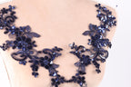 A close-up view of a mannequin torso wearing a decorative necklace with intricate blue sequin and floral patterns.