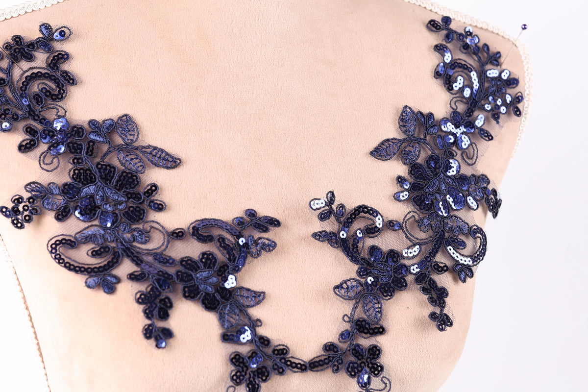 A close-up view of a mannequin torso wearing a decorative necklace with intricate blue sequin and floral patterns.