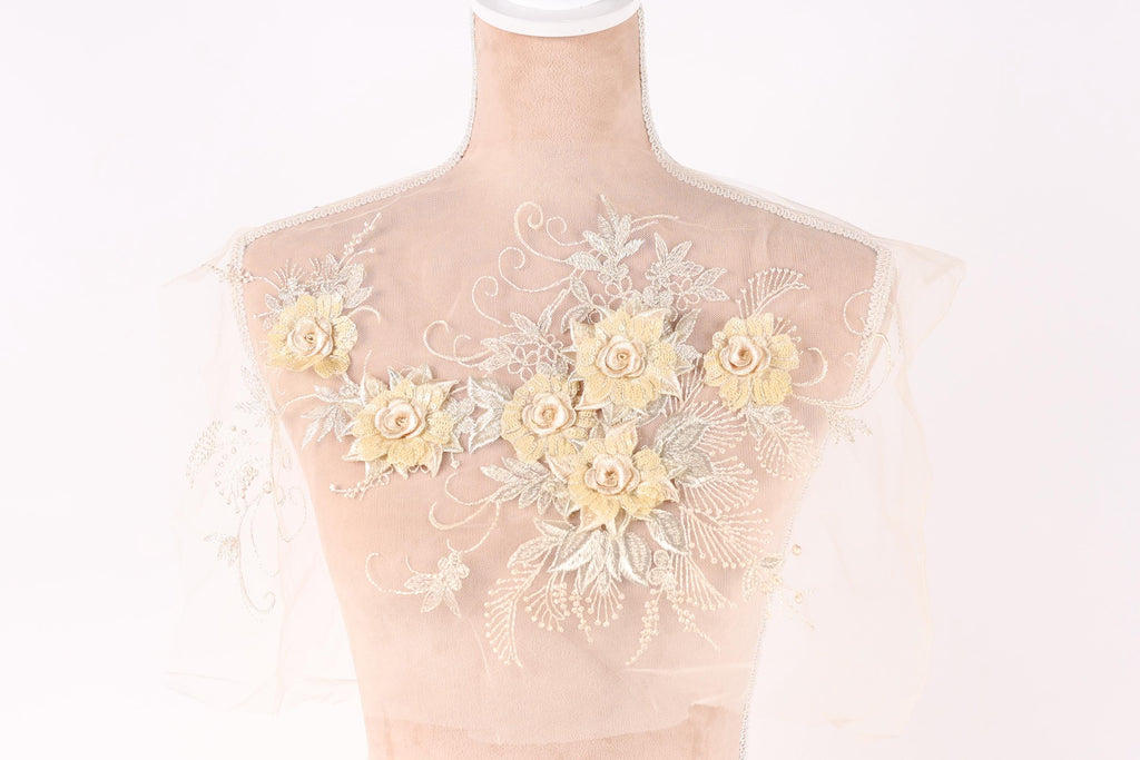 A mannequin with a sheer, lace-like fabric on its back, adorned with delicate yellow flowers and leaves.