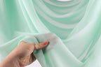 A hand holding a piece of light green fabric, with the fingers visible.