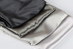 a close-up view of three different colored satin fabrics, including black, gray, and white, arranged in a layered fashion.