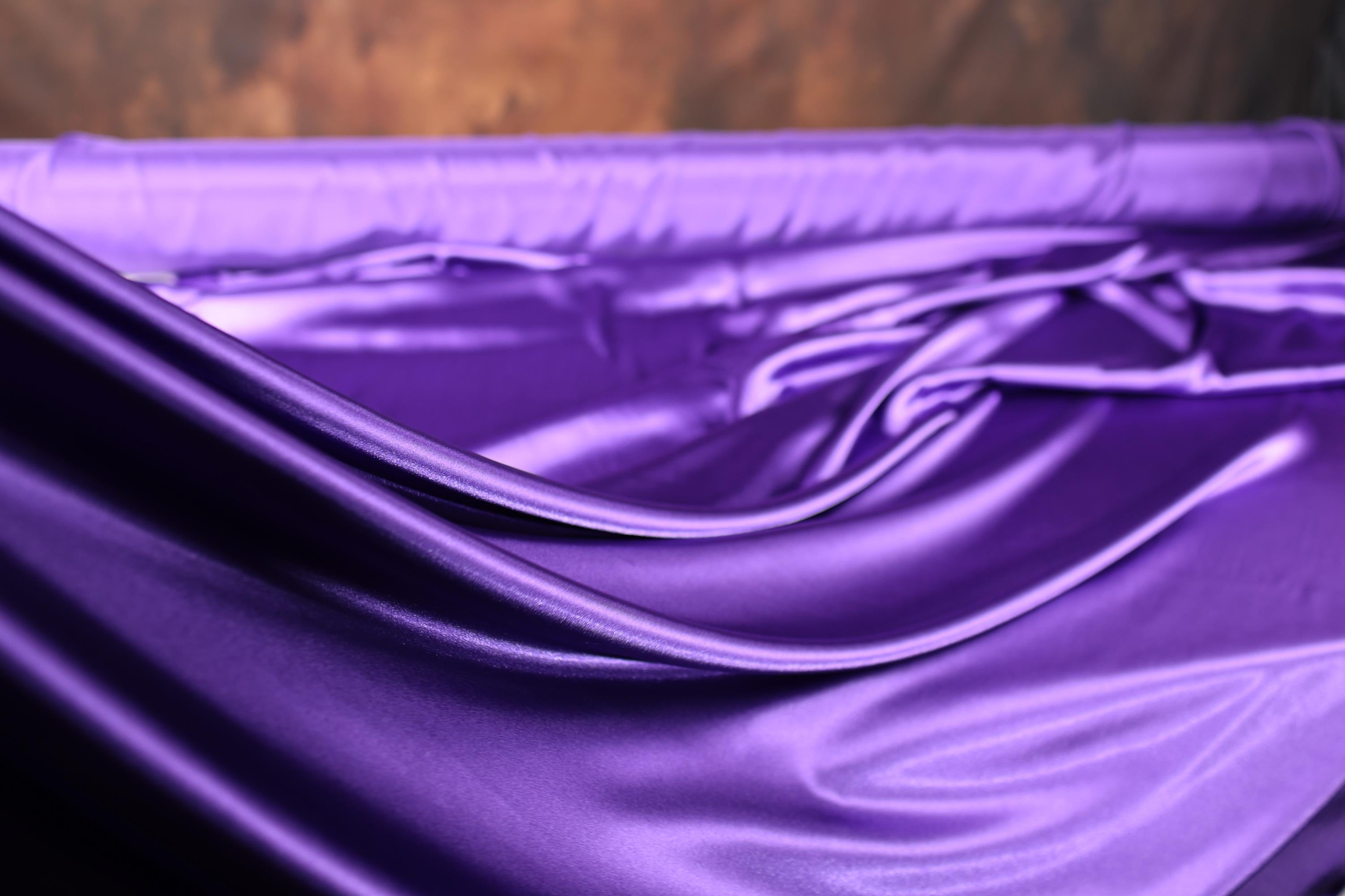 a close up of a purple sheet on a bed