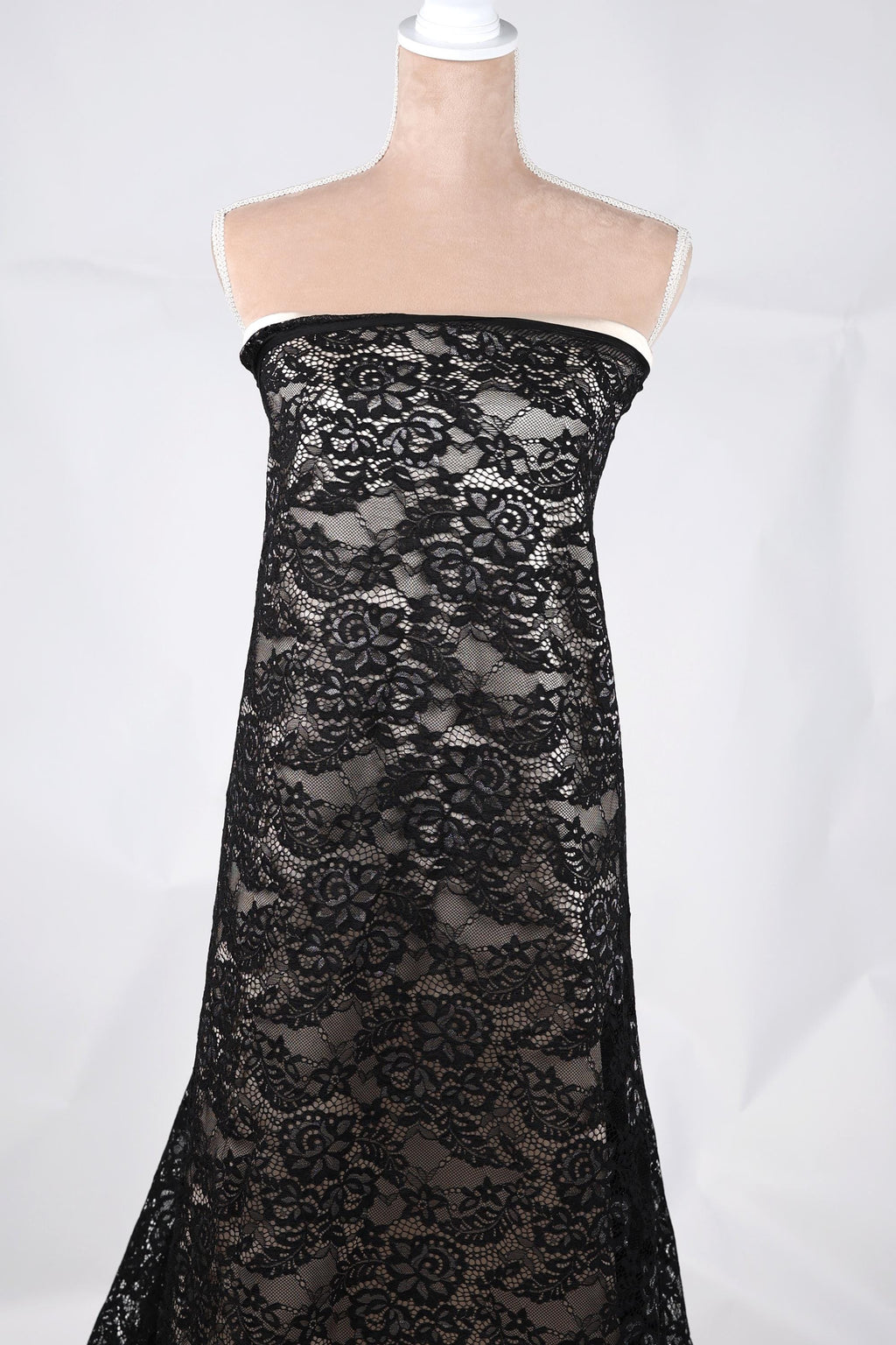 A mannequin wearing a black lace dress with a floral pattern.
