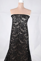 A mannequin wearing a black lace dress with a floral pattern.