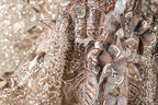 The image is a close-up of a fabric with intricate gold and silver embroidery, including flowers and leaves. The fabric appears to be a decorative piece, possibly used for clothing or other textile applications.