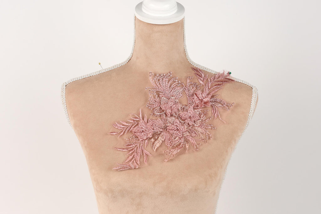 A mannequin with a pink floral embroidered on its shoulder.