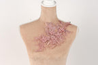 A mannequin with a pink floral embroidered on its shoulder.