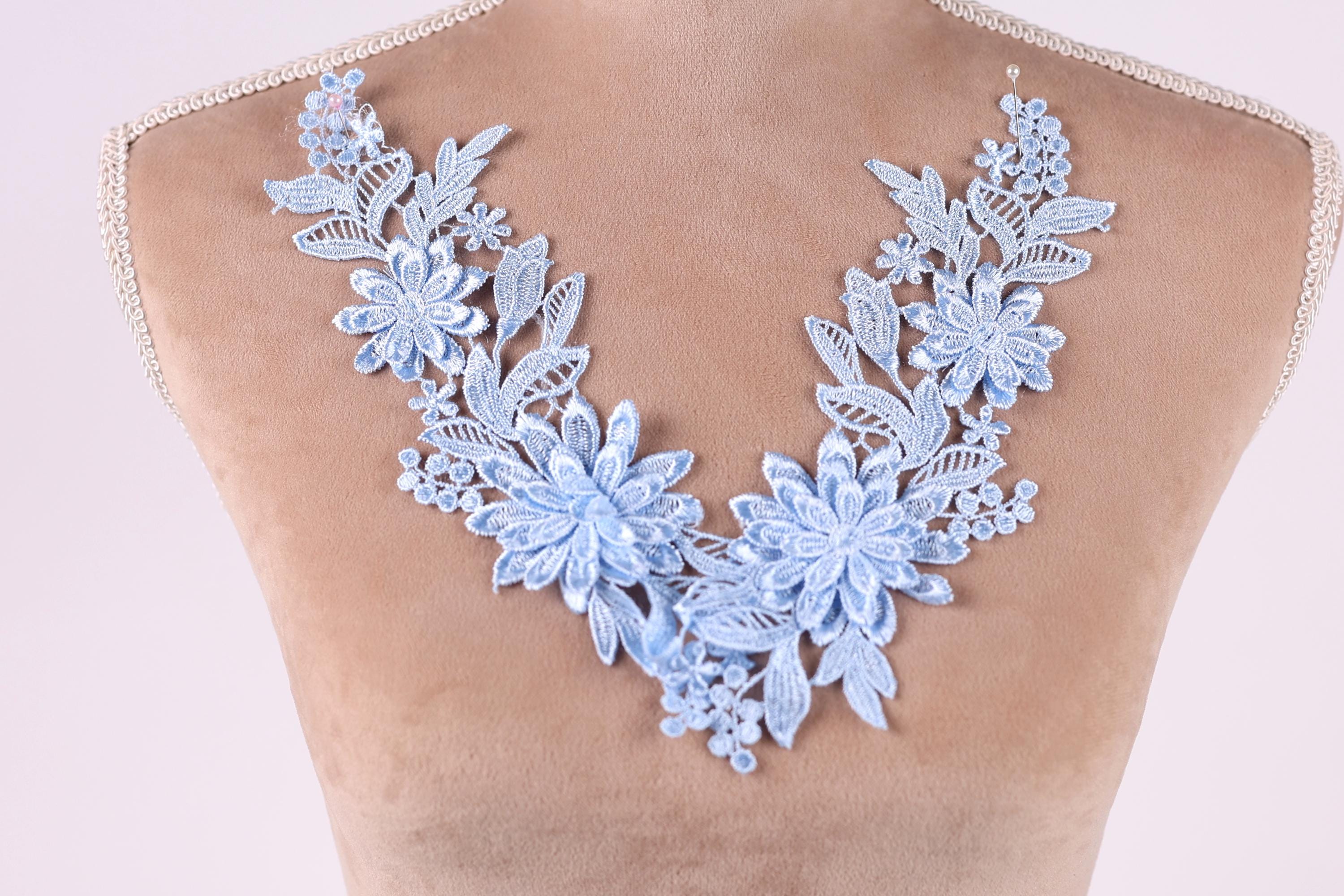 A close-up of a mannequin wearing a necklace with a floral design in blue and white colors.