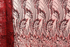 a close-up view of a fabric with a repeating pattern of red and black floral designs. The pattern is intricate and detailed, with the red and black colors creating a striking contrast against the fabric's texture. The fabric appears to be made of a material with a floral or leaf-like pattern, which adds a sense of depth and dimension to the image.