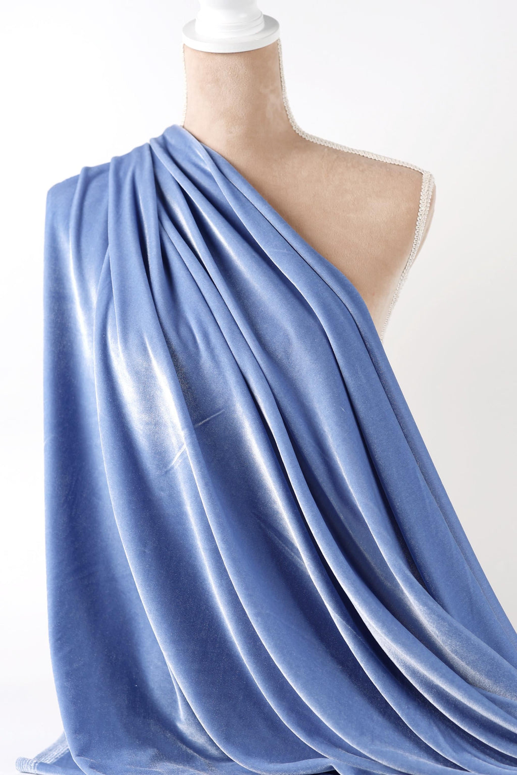 A mannequin wearing a blue draped fabric draped over its body.