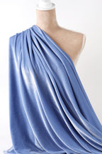 A mannequin wearing a blue draped fabric draped over its body.