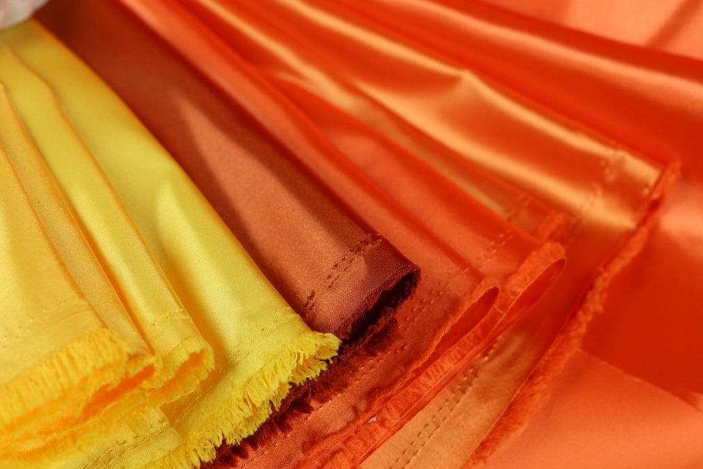 A close-up view of a variety of colorful fabrics, including yellow and orange, arranged in a visually appealing manner.