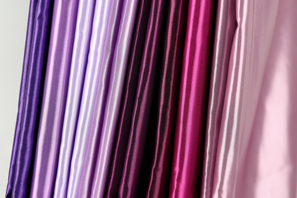 A collection of colorful fabric swatches in various shades of purple, pink, and red.