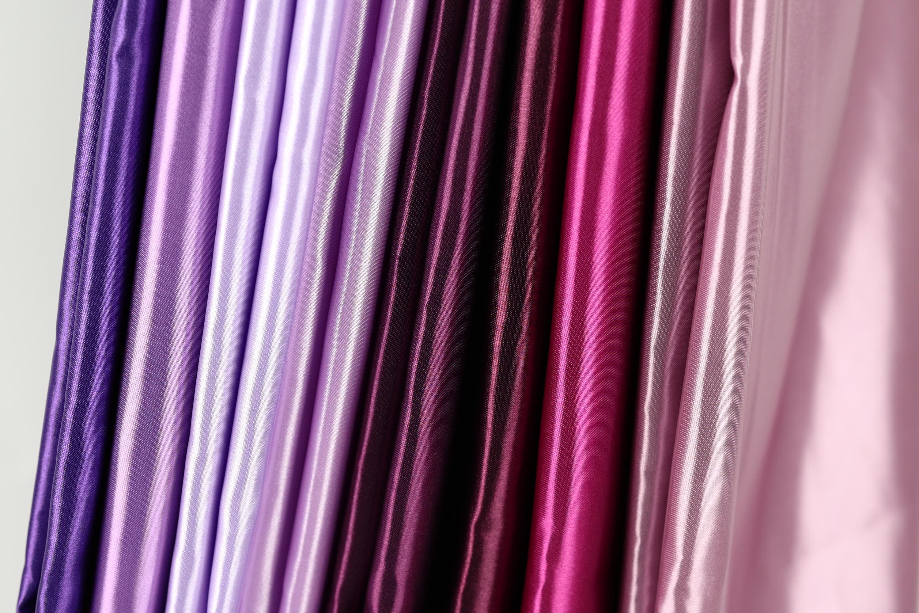 A collection of colorful fabric swatches in various shades of purple, pink, and red.