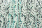 a close-up view of a fabric with a repeating pattern of green and black sequin designs. The pattern consists of various lines and shapes, creating a visually striking and intricate design. The fabric appears to be a light green color, which contrasts with the dark green and black sequin elements. The image does not contain any text or other discernible objects, and the focus is solely on the detailed pattern of the fabric.
