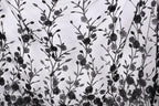 a close-up view of a black and white fabric with a repeating floral pattern. The pattern consists of numerous black flowers and leaves, arranged in a repeating design across the fabric. The fabric appears to be made of a sheer material, allowing the intricate details of the floral pattern to be visible.