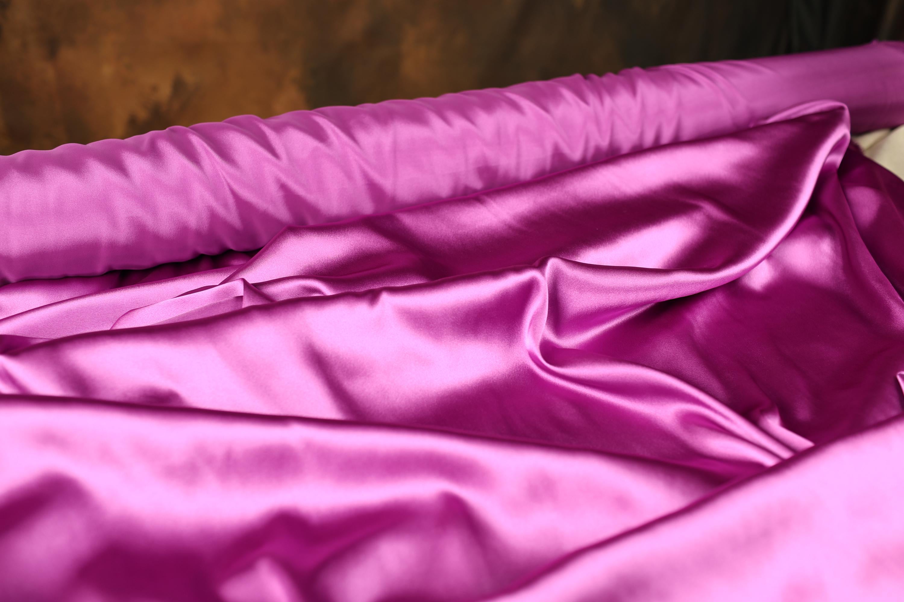 a bed with a pink comforter and a brown headboard