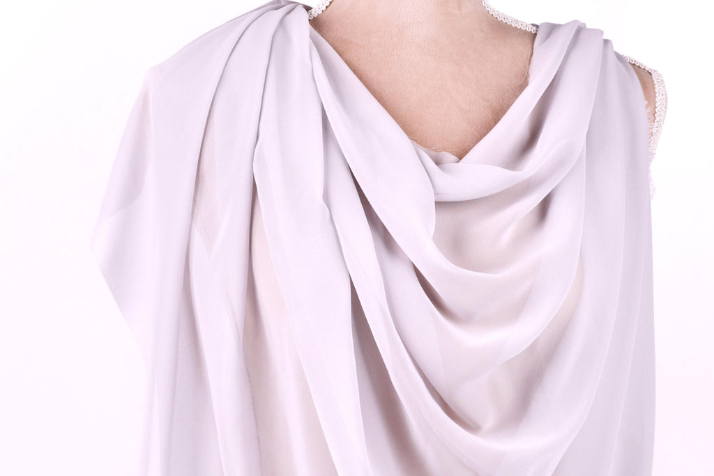 A close-up view of a draped, flowing white fabric draped over a person's shoulder.