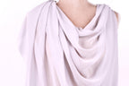 A close-up view of a draped, flowing white fabric draped over a person's shoulder.
