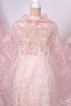 a close-up view of a delicate, pink lace fabric with a floral pattern. The fabric appears to be made of sheer material, giving it a soft and delicate appearance.