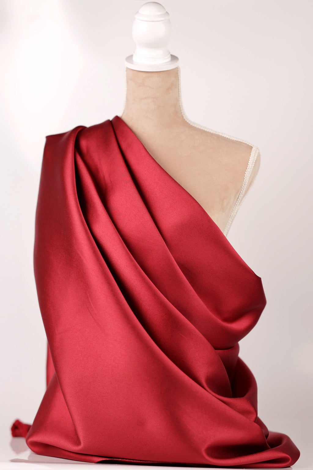 A mannequin is wearing a red satin fabric draped over its body.